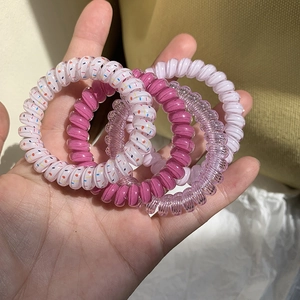 Set of four colorful spiral phone cord hair ties in pink, purple and polka dot patterns