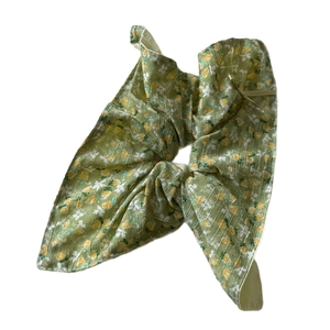 Green floral bow hair scrunchie with yellow blossoms on a white background