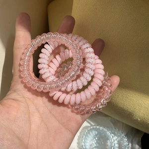 Close-up of four spiral telephone wire hair ties in various shades of pastel pink color