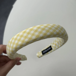 Close-up of yellow gingham padded headband featuring a black handmade textile label