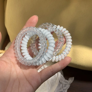 Close-up of four spiral telephone wire hair ties in diverse colors on a person's palm