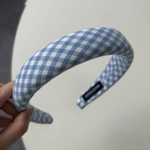 Detailed macro view of blue plaid fabric headband featuring a woven HAND MADE textile label