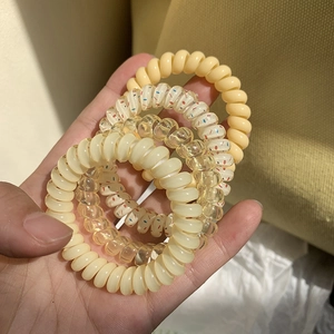 Set of 4 pastel spiral telephone wire hair coils shown held in hand on warm background