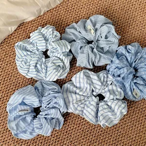 Set of blue and white striped fabric scrunchies on a textured background for hair styling