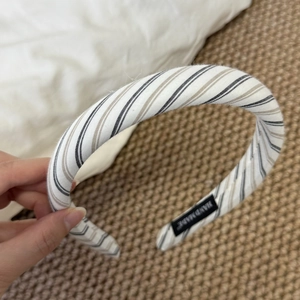 Close-up of handmade striped fabric sponge headband with a black handmade woven label