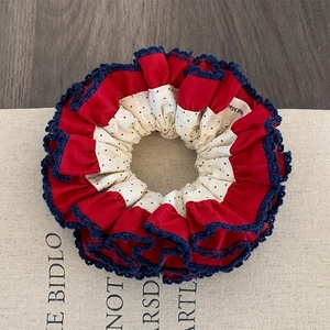 Retro red polka dot scrunchie with lace trim and handmade label on vintage canvas background