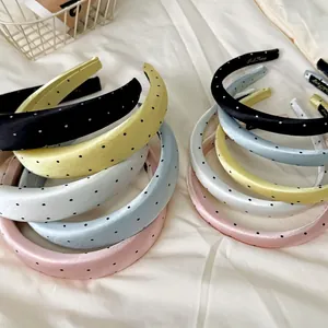 Satin polka dot padded headbands in various colors on a soft white fabric background