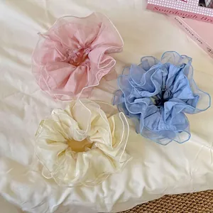 Trois chouchous géants en organza transparent rose, bleu clair et blanc crème