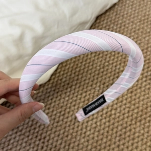Detail of pink and white striped sponge headband with handmade label and fabric texture