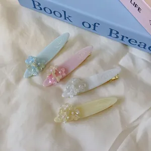 Lot de quatre barrettes à fleurs pastel avec perles sur fond élégant en tissu blanc