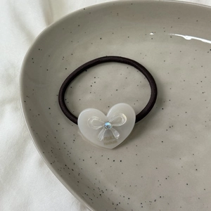 Vue macro d'un chouchou en acétate avec cœur, nœud en cristal et texte France handmade