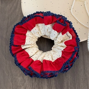 Red polka dot scrunchie with crochet lace and handmade label on a wooden desk