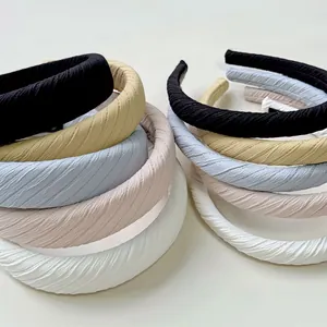 Detail view of stacked pleated fabric headbands in various macaron colors and soft textures
