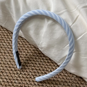 Detailed shot of light blue striped fabric headband with a small black brand label