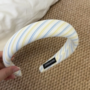 Close-up of padded sponge headband featuring blue and yellow stripes on white fabric