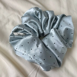 Detailed macro shot of light blue satin polka dot scrunchie with silky texture