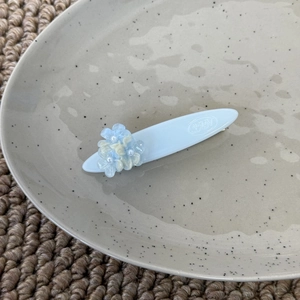 Détails de la pince à cheveux fleurie bleu clair avec perles et logo SAN gravé