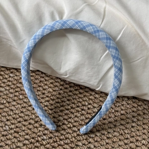 Detail view of light blue checkered fabric headband with classic gingham pattern texture