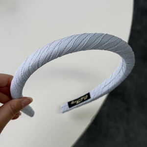 Detail of light blue sponge headband with elegant pleated diagonal stripe texture