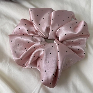 Detail of pink satin polka dot scrunchie showing smooth texture and elegant folds