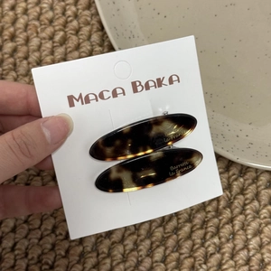 Detail view of two tortoiseshell acetate leaf hair clips on branded card packaging