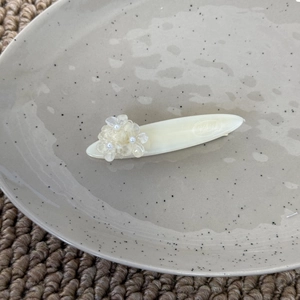 Détail d'une pince à cheveux blanc crème avec fleur mate et accents de mini perles