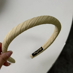 Detail showing the inner seam of beige pleated sponge headband with a black brand label