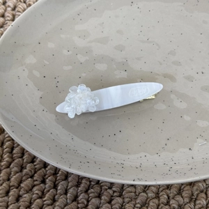 Détail macro d'une barrette à cheveux effet marbre blanc avec fleur et perle décoratives