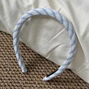 Detailed close-up of blue and white checkered fabric headband on a soft white cushion