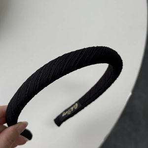 Detail of black sponge headband with twill pleated fabric and golden logo on inner band