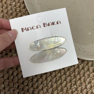 Close-up of elegant pearlescent oval hair clips with metal base on display card
