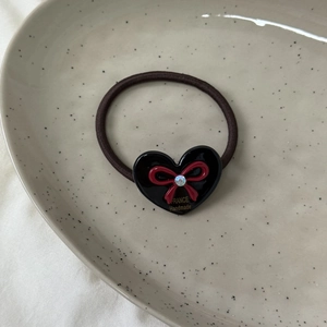 Gros plan sur un chouchou en acétate noir avec nœud rouge et cristal brillant de qualité