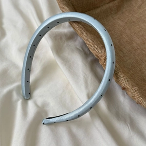Detail of light blue padded headband with black polka dots on glossy satin fabric