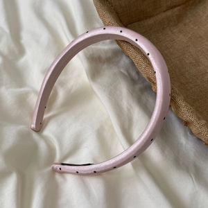 Close-up of pink satin headband with black polka dots and non-slip inner lining texture