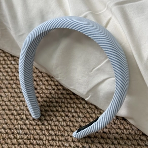 Close-up of blue and white striped fabric headband on a textured linen background