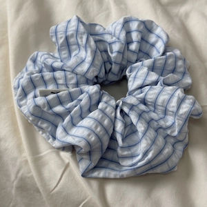 Detail of blue and white striped fabric scrunchie with soft ruffled texture and small label