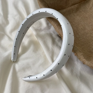 Close-up of thick white headband with black polka dots in premium satin fabric