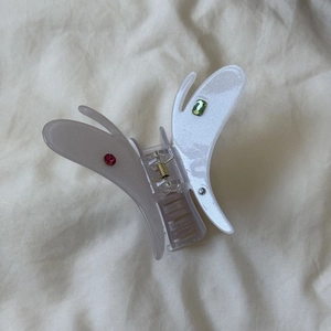 Détail de la pince à cheveux papillon en acétate blanc translucide avec strass colorés