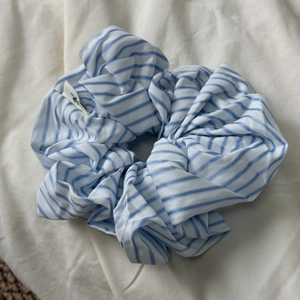 Close-up of blue and white striped fabric scrunchie with detailed logo tag on soft background