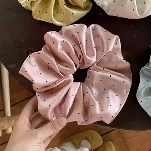 Makroaufnahme großer gepunkteter Seiden-Scrunchies in Pastellfarben auf Holz