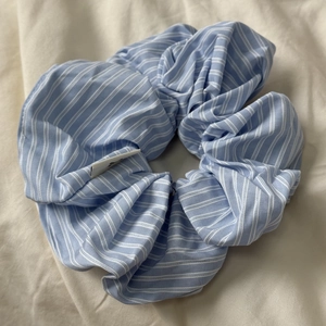 Detailed close-up of blue and white striped fabric scrunchie with soft pleated texture