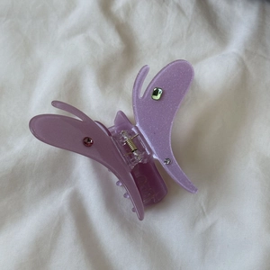 Détail d'une pince à cheveux papillon en acétate violette avec des strass colorés
