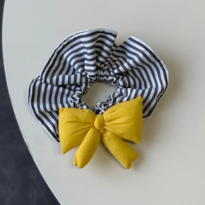 Detail of black white striped hair scrunchie with puffy yellow cotton bow knot
