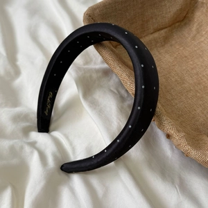 Detail of padded black polka dot satin headband with elegant gold brand embroidery