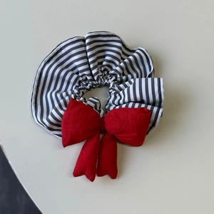Detailed view of a striped scrunchie featuring a prominent 3D red cotton-filled bow tie