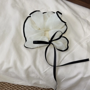 Detail of white chiffon scrunchie with black trim and long satin ribbon bow accessory