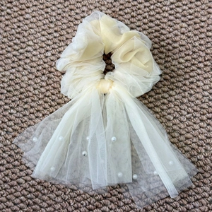 Λεπτομέρεια από κρεμ οργάντζα λαστιχάκι μαλλιών με μακριές κορδέλες και πέρλες