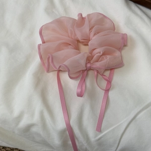 Close-up of pink sheer organza scrunchie with ribbons and delicate wavy edges