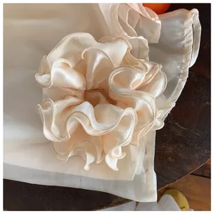 Elegant champagne satin scrunchie with layered ruffle design for stylish hair buns