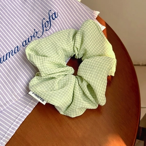 Dettaglio dell'elastico scrunchie a quadretti verde chiaro su tavolo in legno